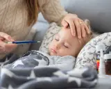 Matka mierzy gorączkę śpiącemu dziecku, troskliwa opieka nad zdrowym dzieckiem, gdy jest chore.