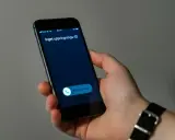 En hand håller en mobiltelefon med ett inkommande samtal. Skärmen visar "Inget uppringnings-ID" och en knapp för att svara.