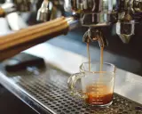 Espresso spływa do szklaneczki. Czy ekspres do kawy pobiera dużo prądu? To zależy od modelu, ale ten wygląda na profesjonalny.