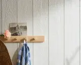 En träpanel inomhus inspiration med en ljus trähylla, en gammal bild, en blomma och en handduk.