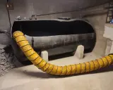 Gros réservoir de fioul noir, vide, avec un tuyau jaune flexible. Projet ma prime rénov cuve fioul en cours.