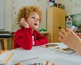 Chłopiec z kręconymi włosami, u którego podejrzewa się zespół Aspergera, uczy się z kart obrazkowych.