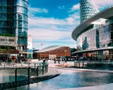 Scena urbana moderna con persone che passeggiano, un edificio IBM e grattacieli specchiati. Immagini di vita quotidiana in una città dinamica.