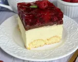Pyszny sernik gotowany z galaretką malinową, udekorowany maliną i miętą, na biszkoptowym spodzie.