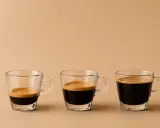 Drei Espressotassen zeigen den americano kaffee unterschied: von wenig Espresso bis zu mehr.