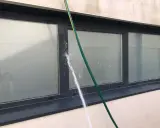Agua salpicando sobre un perfil de aluminio de ventana, creando condensación y gotas.