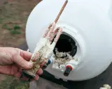 Main d'homme tenant une résistance de chauffe-eau entartrée, montrant l'importance d'éliminer le calcaire pour un bon fonctionnement.