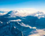 Majestatyczne góry z Aconcagua, skąpane w słońcu, otoczone chmurami. Widok z lotu ptaka na ośnieżone szczyty.