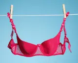 Ein roter BH mit Herzchen-Trägern trocknet an der Wäscheleine. Frisch gewaschen und bereit für den nächsten Einsatz.