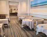 Élégant bistro à Saint-Malo, tables dressées, ambiance chic avec une fresque marine au mur.