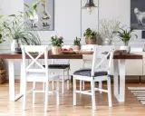 Comedor con mesa de madera oscura y sillas blancas, un ejemplo perfecto de cómo combinar muebles blancos y madera oscura. Plantas y cuadros decoran el espacio.