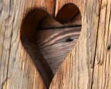 Corazón tallado en madera con textura de envejecer madera, mostrando vetas y grietas que cuentan historias.