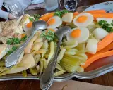 Plat généreux d'un restaurant du terroir : viandes, légumes racines et légumes verts, prêt à être dégusté.