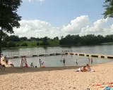 Słoneczny dzień na jednej z najpiękniejszych plaż na Mazurach. Ludzie odpoczywają na piaszczystym brzegu i w wodzie, ciesząc się latem.