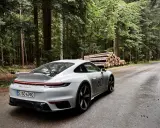 Ein weißer Porsche 911 mit der Nummer 60 auf der Seite fährt auf einer nassen Waldstraße. Die Beschleunigung von 0 auf 100 km/h ist beeindruckend.