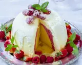En imponerande dessert till nyår: en kupolformad glassbakelse med lager av gul och rosa glass, dekorerad med färska bär och mynta.