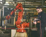 Un disegnatore meccanico opera un braccio robotico in una fabbrica. Il suo stipendio è ben meritato per la precisione richiesta.