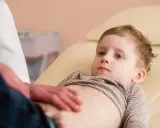 Un bambino viene visitato per sospetto neuroblastoma. Il medico gli tocca delicatamente l'addome.