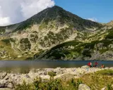 Grupa turystów podziwia najpiękniejsze góry w Europie. Jezioro odbija skaliste zbocza i szczyt.