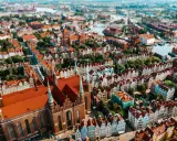 Widok z lotu ptaka na zabytkowe miasto z ceglaną katedrą i kolorowymi kamienicami.