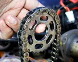 Wymiana rozrządu w Suzuki SX4 1.6 benzyna. Dłoń trzymająca koło zębate i łańcuch rozrządu.
