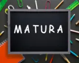Czarna tablica z napisem "MATURA" kredą, otoczona przyborami szkolnymi. To symbol ważnego świadectwa dojrzałości.