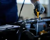 Mechanik w rękawiczce sprawdza poziom oleju za pomocą miarki. To ważny element kontroli, by odma olejowa działała prawidłowo.