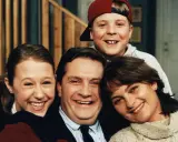 En glad familj, som hämtad ur svenska komedier, ler mot kameran. Pappa, mamma, dotter och son.