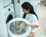 Une femme vérifie le tambour de sa machine à laver, craignant un siphon à machine à laver bouché.