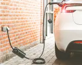 Cargando coche eléctrico a 16 amperios. El cable se conecta a la pared y al vehículo blanco.