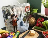 Torba termiczna z postacią z kreskówki i zimowym krajobrazem, obok świeże warzywa i owoce. Idealna, by jak przewieźć jedzenie bez lodówki.