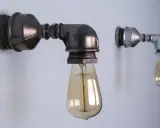 Dwie industrialne lampy z rurek, jedna większa, ciemniejsza, druga mniejsza, jaśniejsza, obie z żarówkami Edisona.