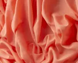 Tessuto arancione con pieghe morbide. Il materiale acrilico, cos'è? Una fibra sintetica versatile e resistente, ideale per abbigliamento e tessuti d'arredo.