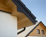 Elegancka podbitka z desek drewnianych pięknie komponuje się z nowoczesną elewacją i ciemnym dachem.