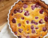 Un délicieux clafoutis framboise tout juste sorti du four, saupoudré de sucre glace. Parfait pour un goûter gourmand.