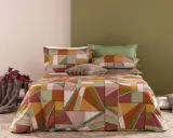 Un letto con copripiumino geometrico dai colori caldi e terrosi. Un perfetto abbinamento colori camera da letto per un tocco moderno e accogliente.