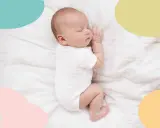 Un bebé duerme plácidamente sobre sábanas blancas. Es una imagen que evoca paz y nos hace pensar en cuando empiezan a dormir mejor los bebés.