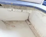 Le fond de cale d'un bateau, sale et moisi, avec des traces d'humidité et de débris.