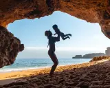 Madre levanta a su bebé en una cueva en el Algarve. Un día perfecto de algarve con niños.