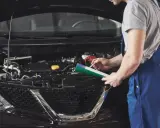 Mechanik sprawdza poziom płynów w silniku, zastanawiając się, czy można dolać płyn hamulcowy.