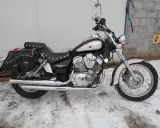 Czarny motocykl Zipp Roadstar 250 z sakwami, błyszczącymi chromami i ozdobnymi nitami, stoi na zaśnieżonym podjeździe.
