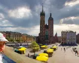 Dziecko na tle Rynku Głównego w Krakowie. To jedno z fajnych miejsc w Krakowie dla młodzieży, pełne życia i zabytków.