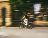 Mężczyzna na rowerze typu s-pedelec pędzi ulicą, rozmyte tło sugeruje dużą prędkość.