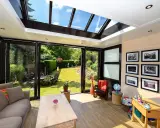 Un salon lumineux avec un canapé confortable, une table basse en bois, et une vue imprenable sur un jardin verdoyant depuis cette **veranda interieur**.