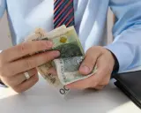 Dłonie liczą polskie banknoty. Zastanawiasz się, ile pracodawca płaci za pracownika przy najniższej krajowej?