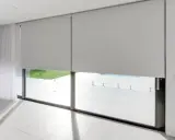 Elegantes persianas enrollables grises ofrecen soluciones para ventanas con mucho sol, bloqueando el deslumbramiento y el calor.