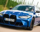 Blauer BMW M3 Competition Kombi rast auf einer Landstraße, die Sonne spiegelt sich im Lack.