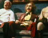 Tre personaggi bizzarri, tra cui Beetlejuice, siedono su un divano in una scena di horror comedy.