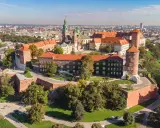 Wawel w Krakowie, z charakterystyczną wieżą widokową, otoczony zielenią i zabytkową architekturą.