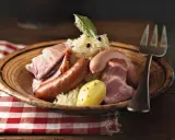 Assiette de choucroute garnie, évoquant son origine alsacienne, avec saucisses, lard, jambon et pommes de terre.